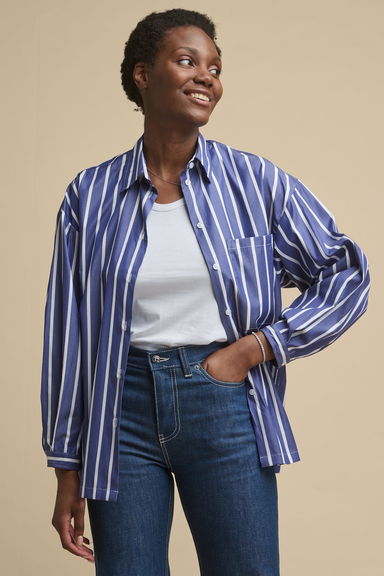 Thigh up image of the front of black female wearing esme long sleeve shirt in blue and white stirpe with one front chest pocket