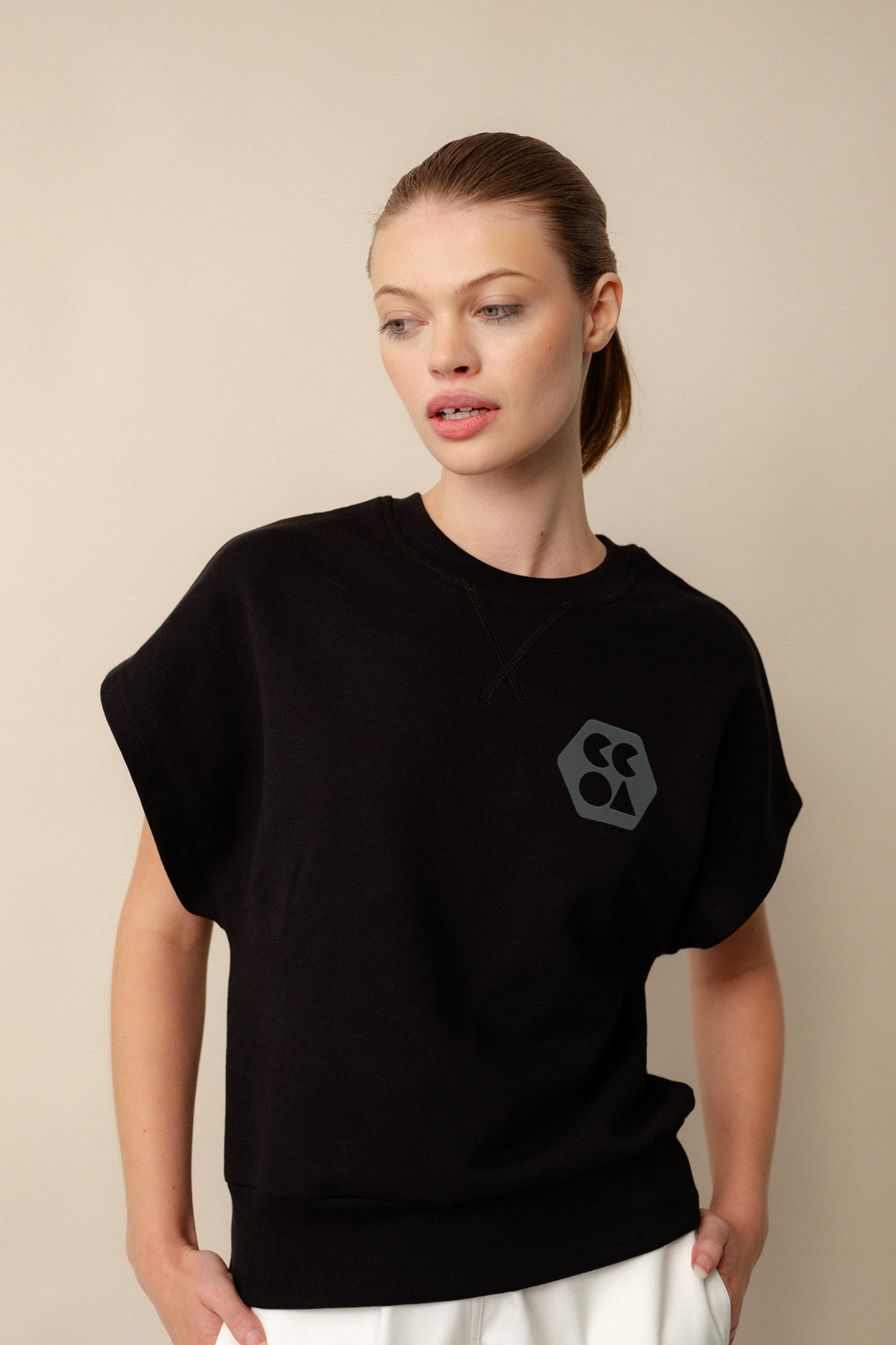 Hip up image of white, brunette female wearing sleeveless sweatshirt plastic free in black. CCOA logo print