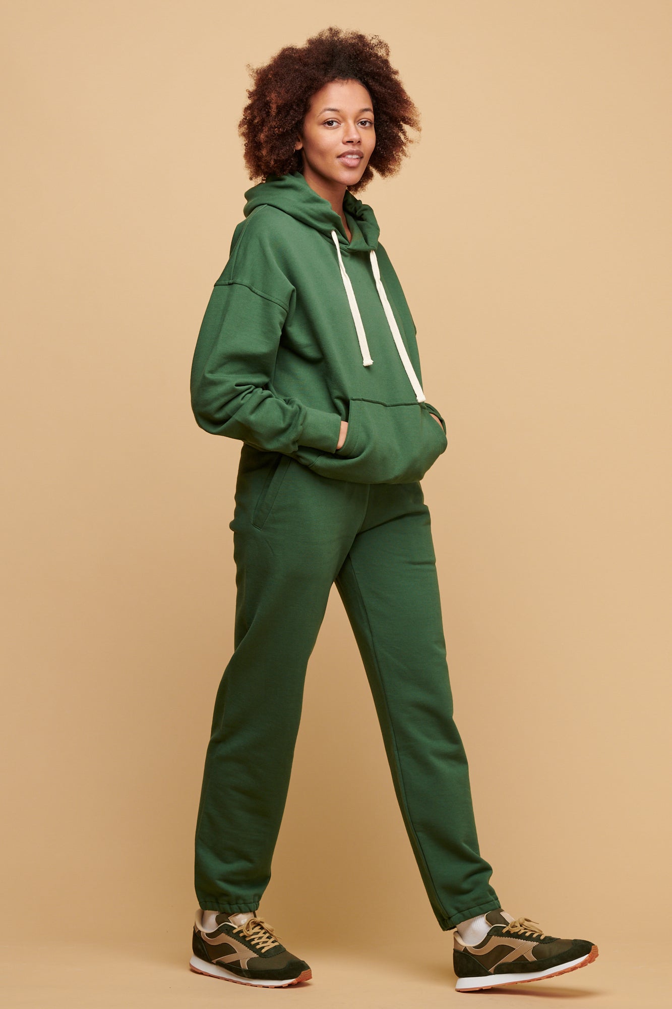 Female wearing Community Clothing matching jogger and hooded sweatshirt set paired with Walsh footwear X Community Clothing Beacon trainers in olive/beige